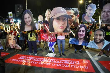 Penunjuk perasaan memegang potret tebusan yang ditawan di Gaza oleh Hamas sejak serangan 7 Oktober, semasa demonstrasi yang menggesa tindakan diambil untuk memastikan pembebasan mereka, di luar ibu pejabat Kementerian Pertahanan Israel di Tel Aviv pada 4 Januari.