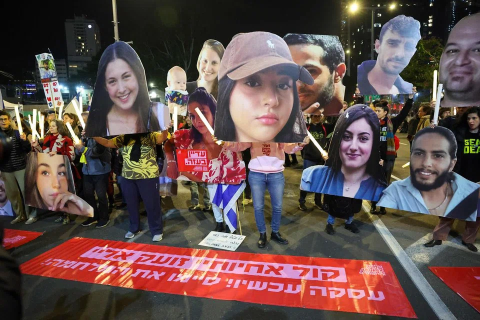 Penunjuk perasaan memegang potret tebusan yang ditawan di Gaza oleh Hamas sejak serangan 7 Oktober, semasa demonstrasi yang menggesa tindakan diambil untuk memastikan pembebasan mereka, di luar ibu pejabat Kementerian Pertahanan Israel di Tel Aviv pada 4 Januari.