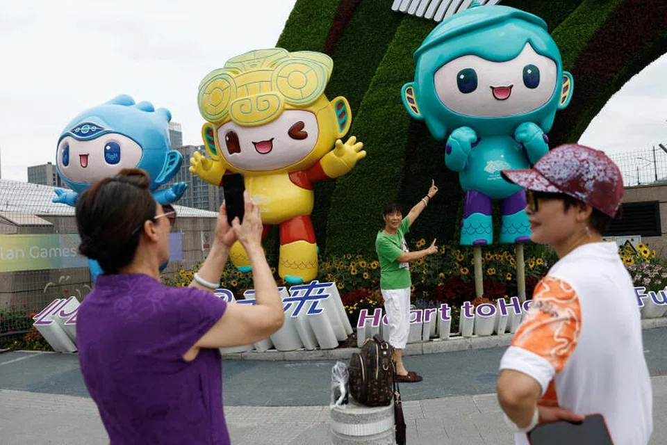CUKUP GHAIRAH: Seorang wanita bergambar di hadapan patung tiga maskot Sukan Asia Hangzhou pada Rabu. 