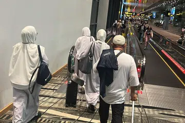 TIDAK DAPAT BERANGKAT: Jemaah kelihatan berjalan ke kawasan imigresen di Terminal 3 Lapangan Terbang Changi selepas pesawat SV837 yang sepatutnya berangkat ke Jeddah pada Jumaat, 5 petang ditangguh hingga Ahad 3.30 petang.