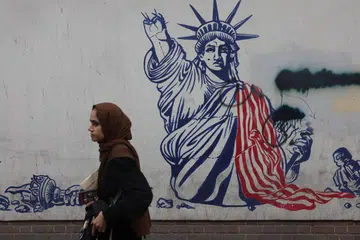 Seorang wanita berjalan berhampiran mural anti-Amerika Syarikat di Teheran, Iran, pada 9 September. Presiden Amerika Syarikat, Encik Donald Trump, meramalkan perang dengan Iran akan berakhir sekitar akhir November, selepas pilihan raya separuh penggal Amerika pada 3 November, dan mendakwa Teheran mahu mencapai perjanjian bagi menamatkan konflik itu.