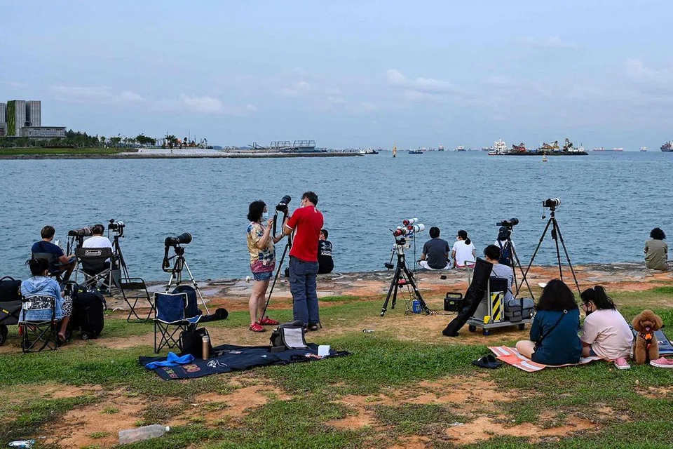 SAKSIKAN FENOMENA: Warga bersiap dengan teropong dan camera untuk menyaksikan gerhana bulan. - Foto AFP