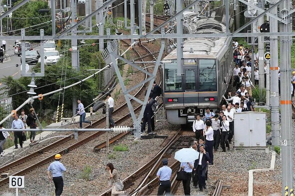 GANGGUAN: Penumpang kereta api terpaksa turun dan berjalan di landasan selepas gempa bumi sekuat 6.1 pada skala Richter melanda Osaka pada 18 Jun 2018.