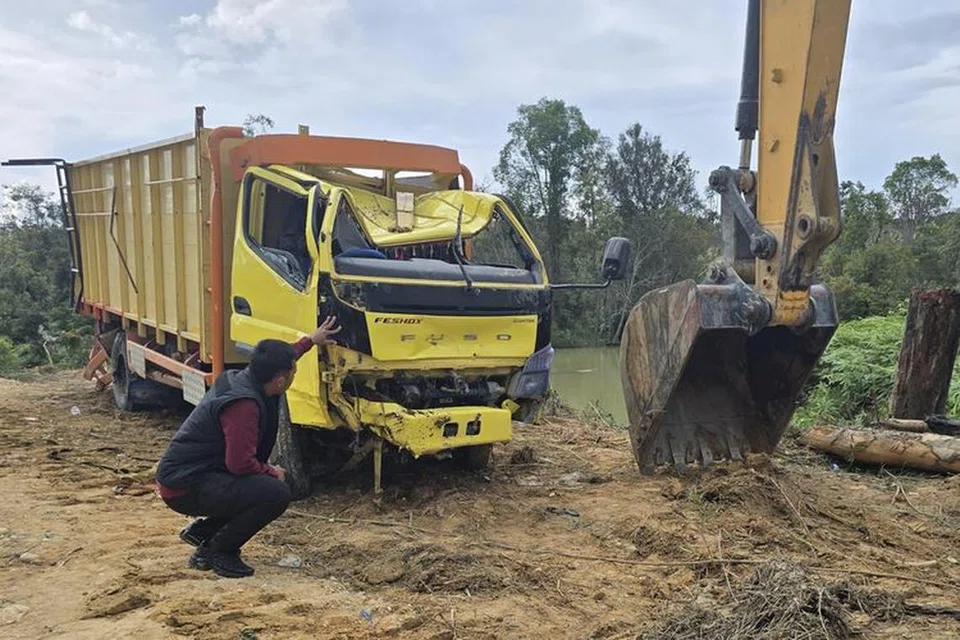Trak yang terhumban ke Sungai Segati, Desa Segati, Pelalawan, Riau, Indonesia, diangkut menggunakan jentera berat ke daratan pada 23 Februari
