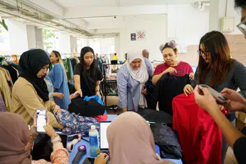 Para sukarelawan MudaSG menyelaras bantuan buat penerima pakaian baju Raya terpakai.