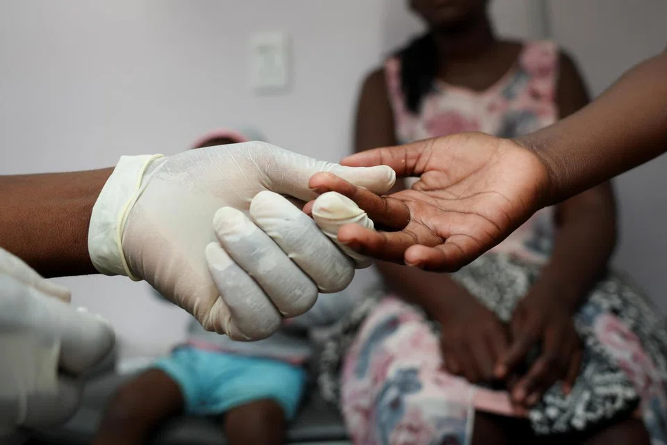 Seorang kakitangan hospital sedang mengambil contoh darah seorang kanak-kanak di Diepsloot, utara Johannesburg, Afrika Selatan.