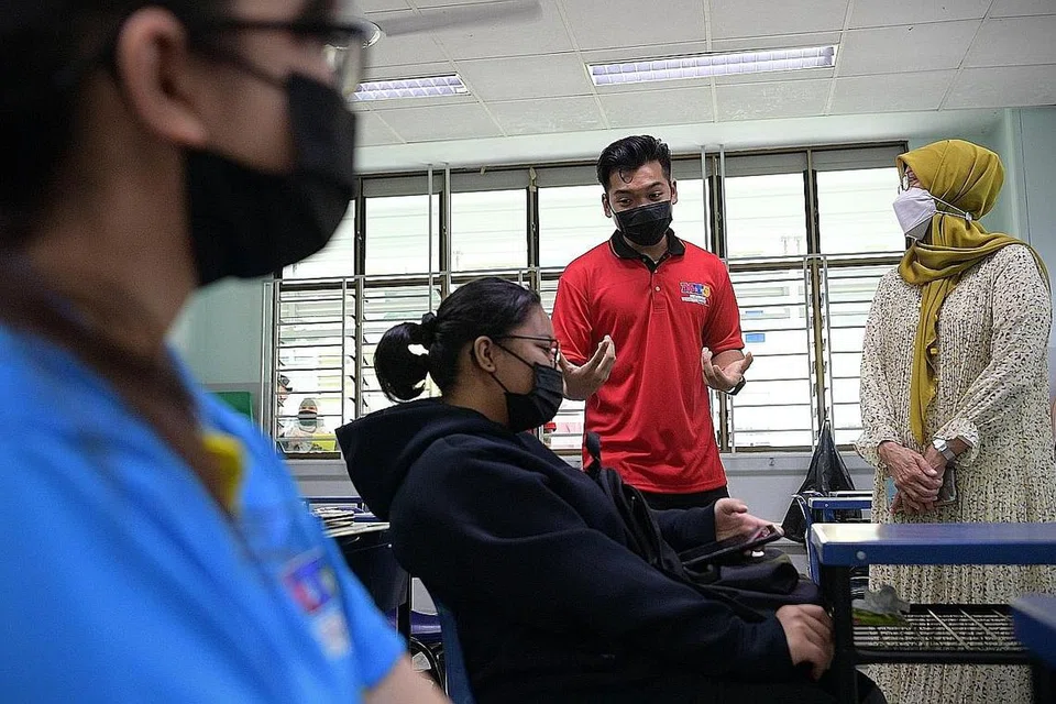 KONGSI ILMU: Mahasiswa Universiti Nasional Singapura, Encik Mirza Nabil Putra Azhar (berdiri) memberi panduan kepada pelajar menengah 3 dan 4 di Sekolah Menengah Marsiling mengenai pilihan melanjutkan pelajaran. Ia merupakan usaha di bawah program pementoran #amPowered@MTS. Turut menyaksikan ialah Ketua Pegawai Eksekutif Yayasan Mendaki, Cik Zuraidah Abdullah (kanan). - Foto BH oleh NG SOR LUAN