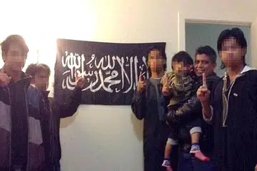 JADI RADIKAL: Zulfikar (dua dari kanan) memuatnaik fotonya bersama anak-anaknya di depan bendera kumpulan pengganas. - Foto fail KEMENTERIAN EHWAL DALAM NEGERI