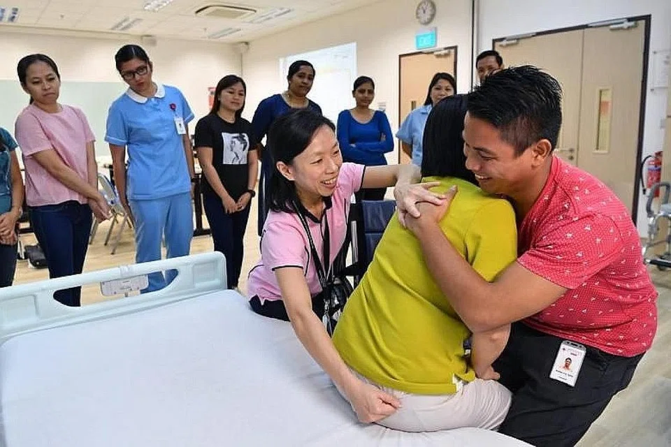 TINGKAT KEMAHIRAN: Ahli fisioterapi utama, Cik Margaret Goh (kiri) menunjuk ajar cara yang betul memindahkan pesakit dari katil ke kerusi roda di Pusat Latihan Masyarakat di Hospital Kwong Wai Shiu. - Foto BH oleh CHONG JUN LIANG