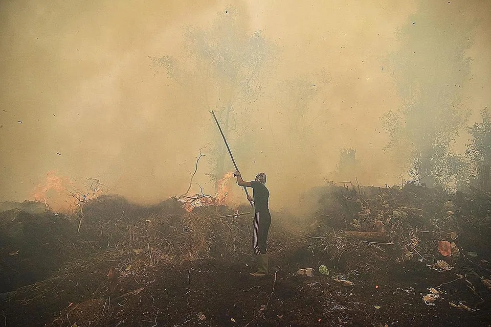 ASAP TEBAL: Kelihatan seorang penduduk kampung cuba menghapuskan kebakaran hutan di kampungnya di Kampar, Riau kelmarin. - Foto AFP