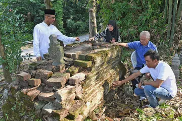 LAWATAN SULUNG KE KUBUR DATUK: Encik Wan Hussin (dua dari kanan) bersama ahli keluarga lain - (dari kiri) cicit Allahyarham Abdul Halim Karto, Encik Muhd Kamel Hussein; dan Cik Norliza Hussein serta suaminya Encik Zaini Rosni, membersihkan kubur Allahyarham yang terletak di tepi Marang Road, pada 7 September lalu. - Foto BM oleh KHALIB BABA