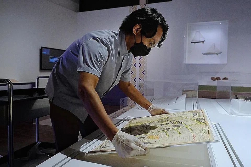 PETA KAMPONG GLAM: Pengurus Kanan, Koleksi dan Pameran di Institusi-institusi Warisan, Encik Muhd Noor Aliff, mengatur peta kawasan itu dari tahun 1949-1954, hasil lukisan tangan pelukis Latiff Mohidin, untuk pameran 'Cerita'. 