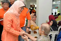 BERSALAMAN: Cik Halimah (kiri) bersalaman dengan seorang penduduk semasa hadir di acara akar umbi di Marsiling semalam. - Foto M.O. SALLEH