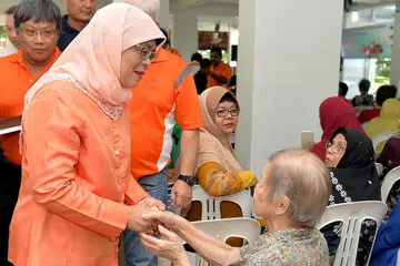 BERSALAMAN: Cik Halimah (kiri) bersalaman dengan seorang penduduk semasa hadir di acara akar umbi di Marsiling semalam. - Foto M.O. SALLEH