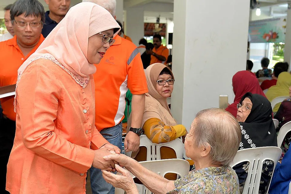 BERSALAMAN: Cik Halimah (kiri) bersalaman dengan seorang penduduk semasa hadir di acara akar umbi di Marsiling semalam. - Foto M.O. SALLEH