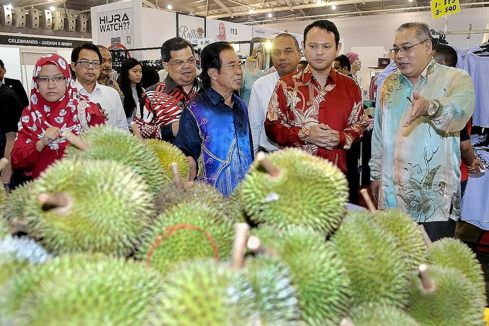 ACARA MALAYSIA FEST: Pengarah Lembaga Pemasaran Pertanian Persekutuan (Fama) Negeri Johor, Encik Zainal Abidin Yang Razali (kanan), mengongsi dengan Encik Zaqy (berbaju merah) tentang durian dari ladang Malaysia di majlis pelancaran Malaysia Fest semalam. Bersama mereka ialah pengarah urusan MegaXpress, Encik Hamzah Abdullah (berbaju biru). - Foto M.O. SALLEH