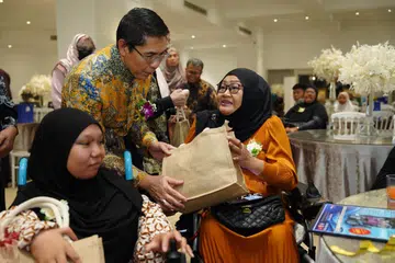 Menteri di Pejabat Perdana Menteri merangkap Menteri Kedua (Pendidikan dan Ehwal Luar), Dr Mohamad Maliki Osman (tengah) bersama penerima bantuan Tabung Amal Aidilfitri (TAA), Cik Nuralysya Abdul Hamid (kiri) yang menghidap sindrom ‘femoral facial’ dan ibunya, Cik Siti Mazurah (kanan).