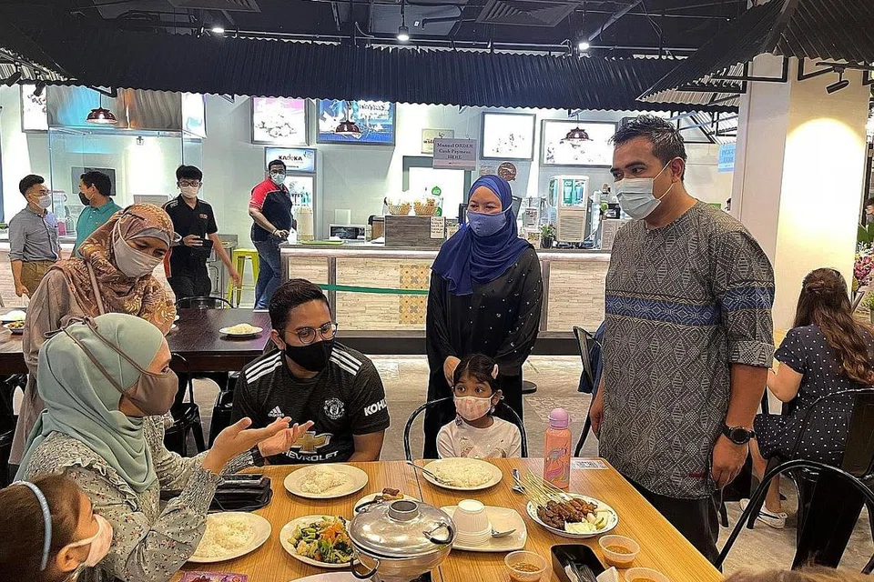 HULUR BANTUAN DI BULAN MULIA: Anggota Parlimen bagi GRC Pasir Ris-Punggol, Encik Sharael Taha (kanan, berdiri), bersama pemilik restoran Asli Village, Cik Samsiah Suliman (bertudung biru), bertemu dengan keluarga yang hadir untuk acara berbuka puasa yang diadakan di restoran tersebut di Downtown East Selasa minggu lalu. - Foto ihsan NTUC CLUB