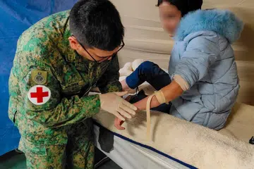 HULUR BANTUAN: Leftenan Kolonel (Dr) Nazirul Hannan Abdul Aziz (kiri), menyediakan talian intravena (IV) untuk pesakit yang akan menerima antibiotik IV. 