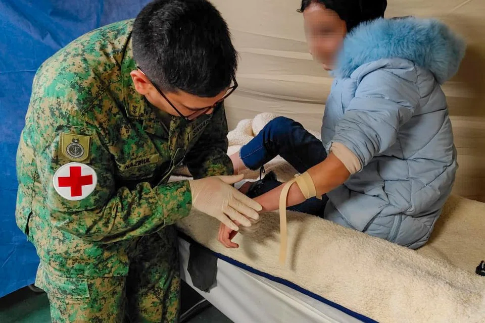 HULUR BANTUAN: Leftenan Kolonel (Dr) Nazirul Hannan Abdul Aziz (kiri), menyediakan talian intravena (IV) untuk pesakit yang akan menerima antibiotik IV. 