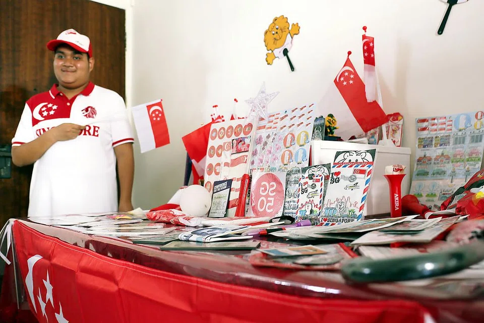 KOLEKSI KESAYANGAN: Encik Muhammad Nur Hakim dengan koleksi barangan yang melambangkan semangat patriotismenya kepada Singapura. Ia berupa pelbagai barangan Singapura yang disimpannya di rumahnya seperti bendera, payung dan topi. - Foto FAKHRURDZI ISMAIL
