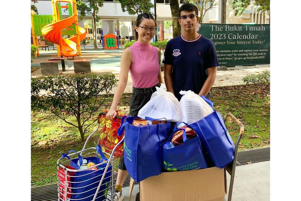 AGIH HABUAN: Cik Emily Yap (kiri) bersama Encik Mikail Firas Abdul Jabbar mengagih habuan Tahun Baru Cina kepada 50 penerima di Clementi Meadows semalam, sementara Cik Nafisa Kapadia menyumbang dengan melukis kad Tahun Baru Cina untuk diberi kepada penerima habuan. - Foto-foto RANGKAIAN BELIA BUKIT TIMAH
