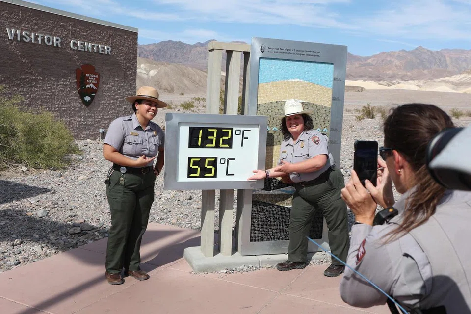 CATAT SUHU TINGGI: Renjer Perkhidmatan Taman Negara Amerika, Encik Gia Ponce (kiri), dan Cik Christina Caparelli, diambil gambar oleh Renjer Cik Nicole Bernard, bersebelahan paparan digital bacaan haba tidak rasmi di Pusat Pelawat Furnace Creek di Death Valley, California, pada 16 Julai.