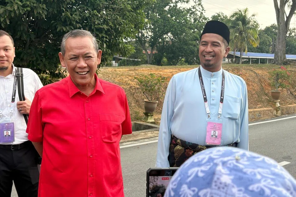 Menteri Besar Negeri Sembilan, Datuk Seri Aminuddin Harun (baju merah) bersama Setiausaha Politiknya, Encik Noor Azman Mohamad (kanan) ketika tiba di pusat mengundi bagi Dewan Undangan Negeri (DUN) Sikamat, sempena Pilihan Raya Negeri (PRN) Negeri Sembilan, pada 1 Ogos.