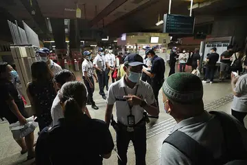 JELASKAN KEADAAN: Pegawai polis dilihat menjelaskan keadaan kepada penumpang terkandas di stesen MRT Jurong East malam semalam. - Foto BH oleh GAVIN FOO
