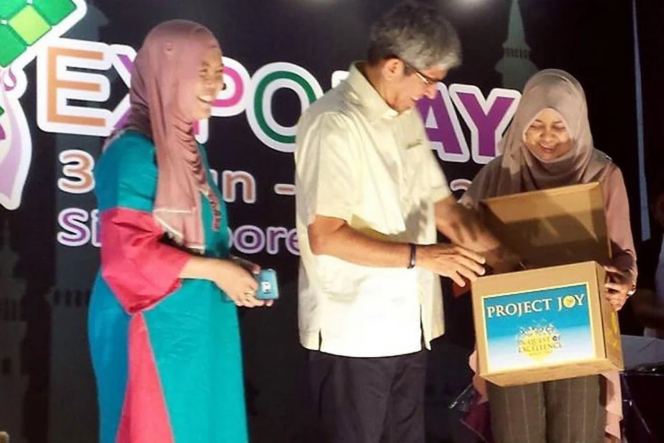 SUMBANGAN LELONGAN KUIH: Dr Yaacob Ibrahim, selaku Pengerusi Mendaki, menerima sumbangan kepada Projek Joy sebanyak $8,230 yang dikumpul hasil lelongan kuih Raya kendalian Divisyen Penyiaran Melayu Mediacorp. Bersamanya ialah Ketua Penyiaran Melayu Mediacorp, Cik Zakiah Halim (kiri) dan Ketua Pegawai Eksekutif Mendaki, Cik Tuminah Sapawi. - Foto MENDAKI