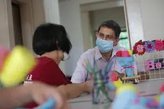 BERINTERAKSI DENGAN BEKAS PENAGIH: Dr Faishal Ibrahim berbual dengan seorang penghuni rumah peralihan The Turning Point sambil memerhatikannya membuat kraf tangan semalam. - Foto BH oleh GIN TAY