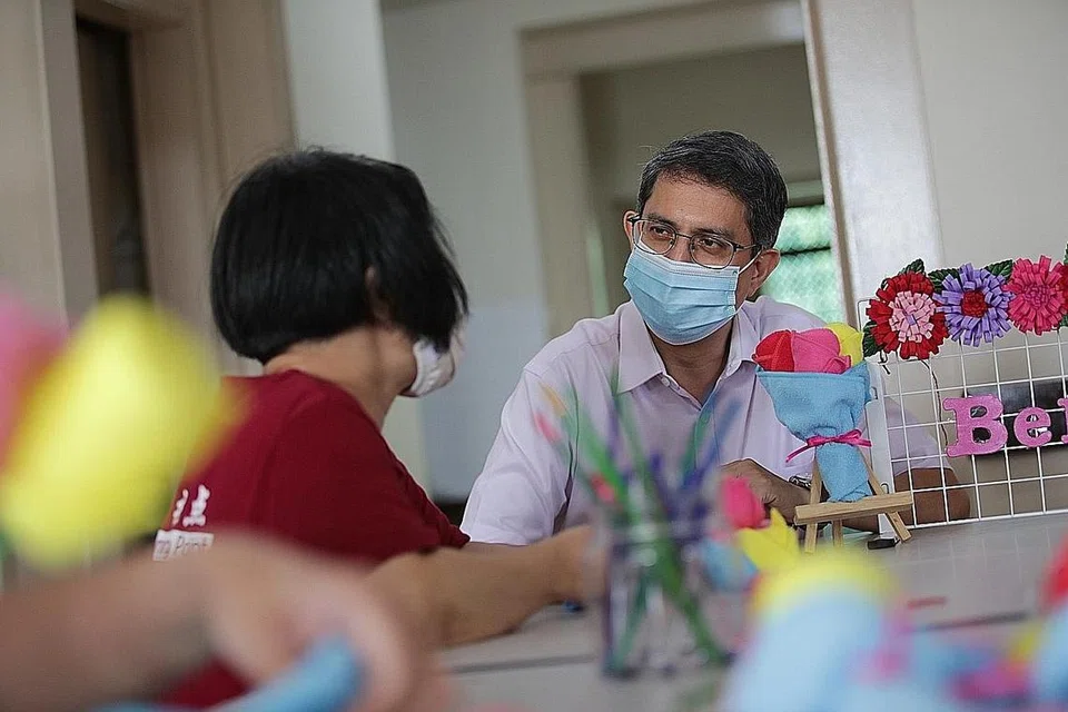 BERINTERAKSI DENGAN BEKAS PENAGIH: Dr Faishal Ibrahim berbual dengan seorang penghuni rumah peralihan The Turning Point sambil memerhatikannya membuat kraf tangan semalam. - Foto BH oleh GIN TAY