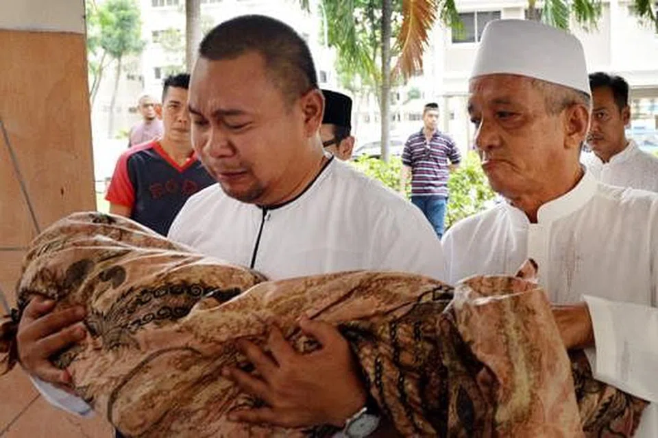 DAKAPAN TERAKHIR: Encik Syahrim tidak dapat menahan air mata sambil mendakap jenazah anak bongsunya yang meninggal dunia selang hampir sebulan selepas Allahyarhamha terjatuh daripada flat. - Foto M.O. SALLEH