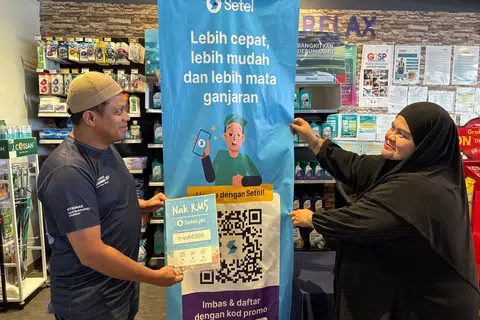 Pekerja stesen minyak Petronas di Sungai Besi, Kuala Lumpur, Cik Siti Rahayu Othman dan Encik Yudin Yunus, menunjukkan poster aplikasi Setel yang akan memudahkan orang ramai membeli petrol RON95.
