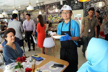 SENANG BERINTERAKSI DENGAN PELANGGAN: Encik Muhd Muhaimin Afandi (bertopi) menghantar makanan yang dipesan kepada pelanggan di Mystical Cafe For All yang terletak di Pusat untuk Orang Dewasa APSN di 11 Jalan Ubi. Kafe tersebut memberi golongan keperluan khas peluang mengalami sendiri bekerja dalam sekitaran pekerjaan yang realistik dan bukan di tempat latihan seperti di bilik darjah sahaja. - Foto JOHARI RAHMAT