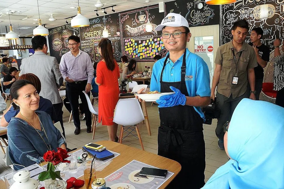 SENANG BERINTERAKSI DENGAN PELANGGAN: Encik Muhd Muhaimin Afandi (bertopi) menghantar makanan yang dipesan kepada pelanggan di Mystical Cafe For All yang terletak di Pusat untuk Orang Dewasa APSN di 11 Jalan Ubi. Kafe tersebut memberi golongan keperluan khas peluang mengalami sendiri bekerja dalam sekitaran pekerjaan yang realistik dan bukan di tempat latihan seperti di bilik darjah sahaja. - Foto JOHARI RAHMAT