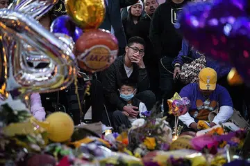 PEMERGIAN DITANGISI: Kesedihan terpapar pada wajah peminat apabila mereka berkumpul di peringatan sementara di kompleks hiburan LA Live, bertentangan Pusat Staples - rumah pasukan Los Angeles Lakers - di Los Angeles, California, untuk memberi penghormatan kepada Kobe Bryant, yang gambar beliau serta anak perempuannya Gianna turut dipaparkan. - Foto EPA-EFE, AFP