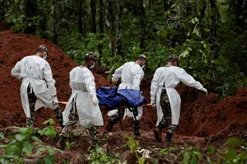 Anggota Pasukan Polis Bersenjata (APF) Nepal membawa satu mayat ke liang lahad di tapak pengebumian beramai-ramai Devghat, Chitwan, pada 30 Ogos 2026. Ratusan mangsa banjir kilat dan tanah runtuh yang belum dikenal pasti dikebumikan selepas pihak berkuasa merekodkan maklumat serta mengambil sampel DNA bagi membolehkan pengecaman dilakukan kemudian.