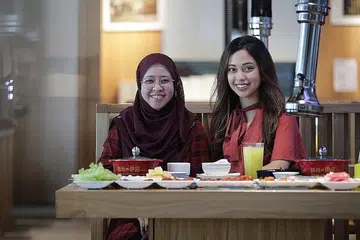 REBUT PELUANG NIAGA: Cik Sharifah Noor Aishah Albukhary (kiri) bersama anaknya, Sharifah Noura Aljunied yang turut mengambil cuti tanpa gaji daripada tugasnya untuk membantu ibunya di restoran. - Foto BH oleh GIN TAY
