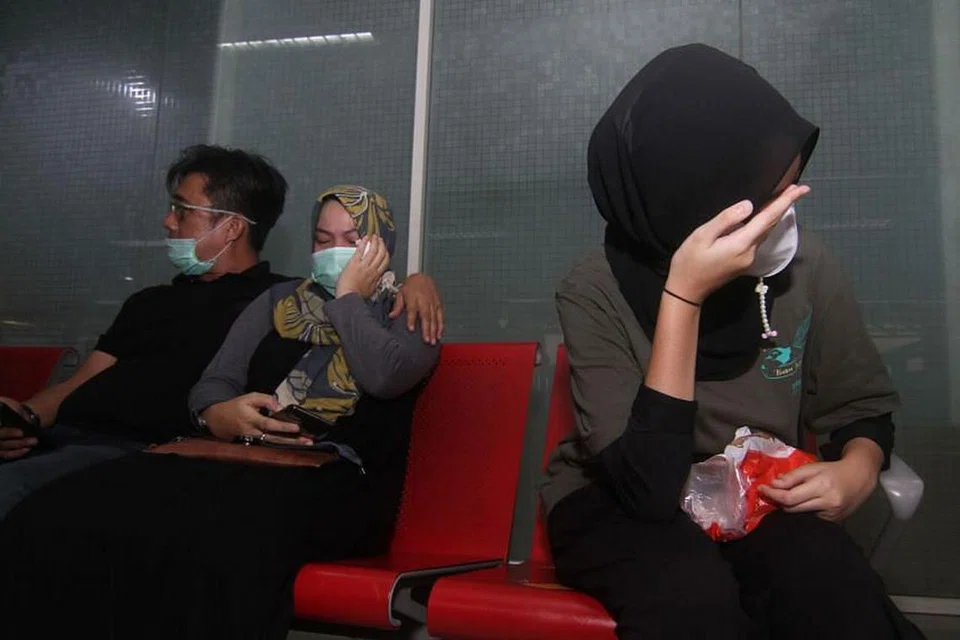 MENANTI DENGAN DEBARAN: Saudara-mara penumpang pesawat Sriwijaya Air yang hilang menanti di Lapangan Terbang Supadio di Pontianak. - Foto AFP 