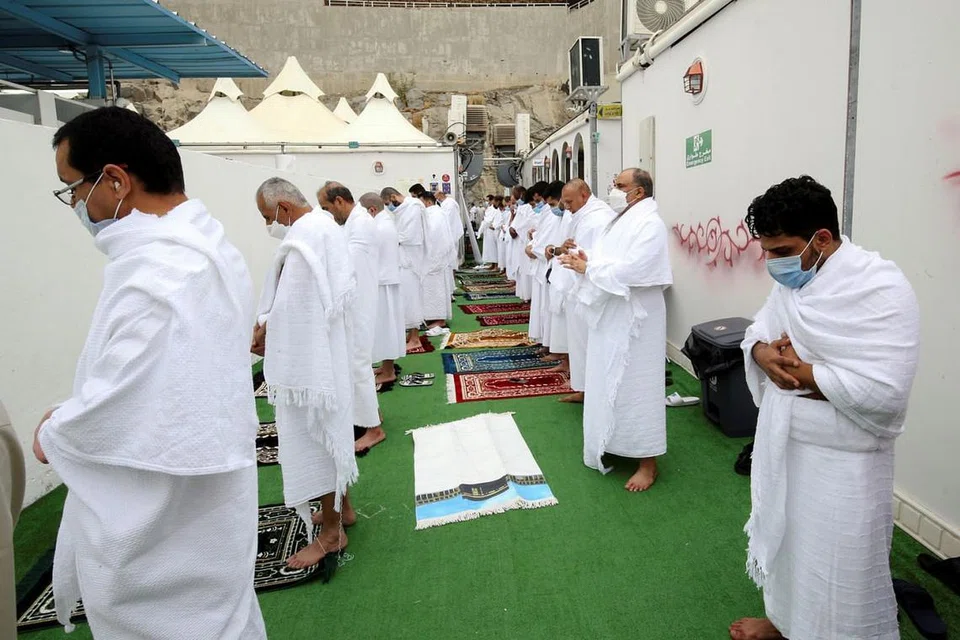 BERSOLAT SAMBIL PATUHI LANGKAH KESELAMATAN: Para jemaah lelaki dalam berihram berpelitup dan bersolat dengan mematuhi jarak fizikal di kawasan khemah mereka di Mina pada Ahad lalu. - Foto REUTERS