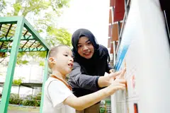 Guru kanan di prasekolah inklusif pertama di Singapura, Kindle Garden, Cik Nur Allysha Osman, bermain bersama salah seorang anak muridnya.