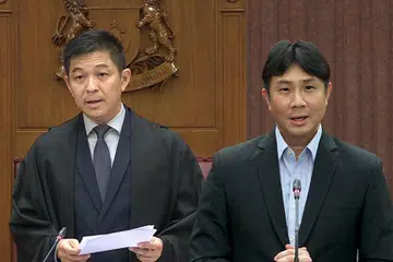 UNGKAPAN KATA DIPERSOAL: Encik Tan Chuan-Jin (kiri) kedengaran menutur kekata lucah dan kesat “****ing populist” ke dalam mikrofon semasa hari pertama perbahasan mengenai Ucapan Presiden pada 17 April, selepas Profesor Madya Jamus Lim menamatkan ucapan kira-kira 20 minit tentang usaha membantu golongan berpendapatan rendah.