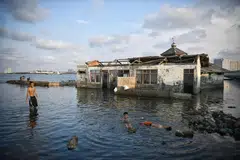 KESAN PEMANASAN GLOBAL: Kanak-kanak bermain di sekitar sebuah masjid yang ditinggalkan di Muara Baru, utara Jakarta, yang semakin mendak dan tenggelam gara-gara paras laut semakin tinggi dek pemanasan global dan penggunaan berlebihan air bawah tanah.  