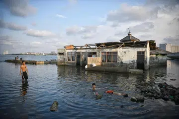 KESAN PEMANASAN GLOBAL: Kanak-kanak bermain di sekitar sebuah masjid yang ditinggalkan di Muara Baru, utara Jakarta, yang semakin mendak dan tenggelam gara-gara paras laut semakin tinggi dek pemanasan global dan penggunaan berlebihan air bawah tanah.  