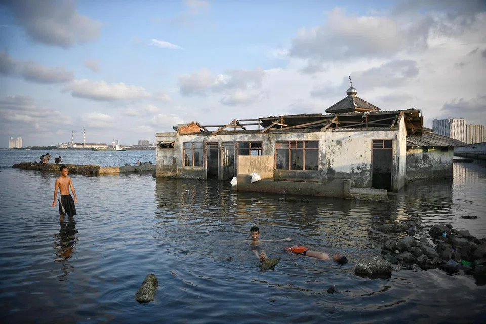 KESAN PEMANASAN GLOBAL: Kanak-kanak bermain di sekitar sebuah masjid yang ditinggalkan di Muara Baru, utara Jakarta, yang semakin mendak dan tenggelam gara-gara paras laut semakin tinggi dek pemanasan global dan penggunaan berlebihan air bawah tanah.  