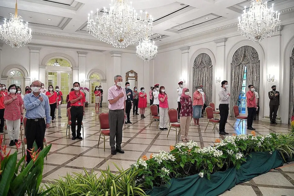 BERSATU ATASI CABARAN: Puan Halimah (depan, tiga dari kanan) yang menghadiri satu majlis sambutan Hari Kebangsaan bersama Perdana Menteri Lee Hsien Loong (depan, dua dari kiri) di Istana semalam berkata dalam ucapan Hari Kebangsaan beliau bahawa warga Singapura harus bersatu mengatasi cabaran Covid-19 bersama. - Foto MCI