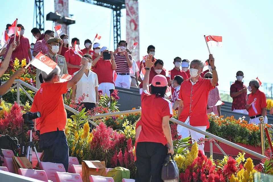 SKALA KECIL, SEMANGAT BESAR: Perdana Menteri Lee Hsien Loong (kanan) mengibar bendera Singapura bersama 100 penonton yang hadir di platform terapung Marina Bay pagi semalam. - Foto BH oleh CHONG JUN LIANG 