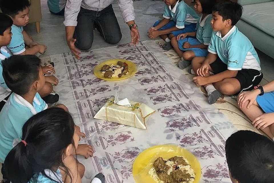 TERTIB MAKAN BERDULANG: Salah seorang anggota SPICE di Sekolah Rendah Eunos, Encik Mohd Nazzer, mengajar murid tentang cara dan tatatertib makan berdulang. Gambar diambil sebelum langkah jarak selamat dan pemakaian pelitup bagi mengekang penularan Covid-19 diwajibkan. - Foto SEKOLAH RENDAH EUNOS