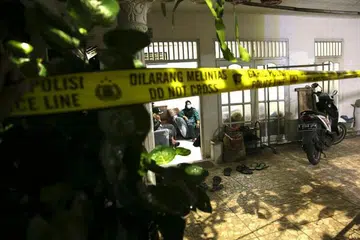 POLIS MENGEPUNG RUMAH KELUARGA PENYERANG: Inilah gambaran rumah wanita bersenjata yang ditembak mati selepas menyerang ibu pejabat polis nasional di Jakarta pada 31 Mac 2021 dengan menggunakan pistol udara piston nitrogen. - Foto DASRIL ROSZANDI/AFP 
